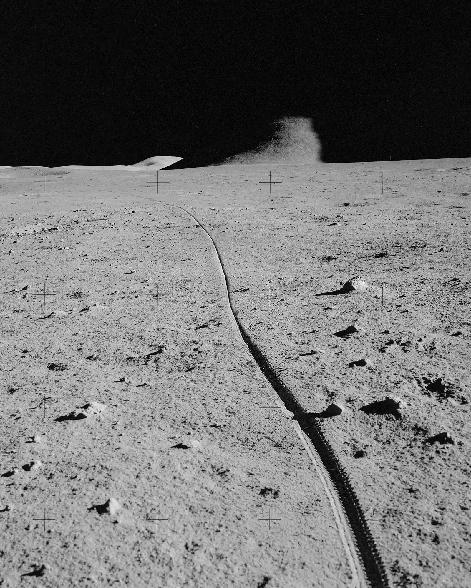 Tire track stretching across the moon landscape under a dark sky